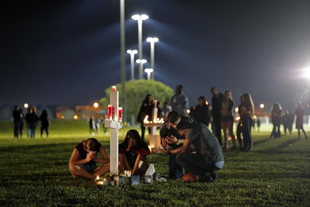 People pray around one of seventeen crosses, after a candlelight vigil for the victims of the Wednesday shooting at Marjory Stoneman Douglas High School, in Parkland. (AP Photo) People pray around one of seventeen crosses, after a candlelight vigil for the victims of the Wednesday shooting at Marjory Stoneman Douglas High School, in Parkland. (AP Photo)