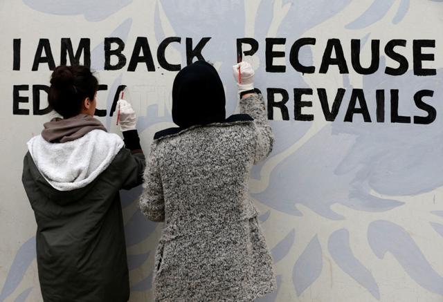 Students help paint a picture of a young man and woman picking up their books, with a phoenix rising and the words: “I am back because education prevails”. (REUTERS) Students help paint a picture of a young man and woman picking up their books, with a phoenix rising and the words: “I am back because education prevails”. (REUTERS)
