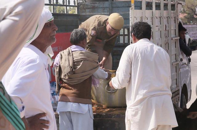 A police official assists in serving food to those at the protest site at Tatiawas toll booth, in Jaipur, on Thursday. (Himanshu Vyas /HT Photo)
