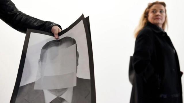 A woman walks past a person holding a photograph, part of the art-installation by Spanish artist Santiago Sierra ‘Political prisoners of contemporary Spain’ at ARCO art fair in Madrid. (AFP)