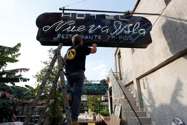 A man fixes the electric wiring of a neon sign, at the workshop and gallery of Nieves. (REUTERS)