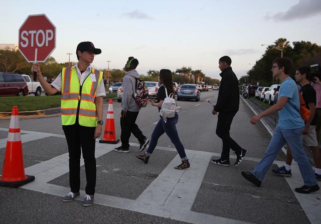 A crossing guard stops traffic for students as they cross to attend classes at Marjory Stoneman Douglas High School for the first time since the shooting that killed 17 people on February 14 at the school on February 28. (AFP Photo) A crossing guard stops traffic for students as they cross to attend classes at Marjory Stoneman Douglas High School for the first time since the shooting that killed 17 people on February 14 at the school on February 28. (AFP Photo)