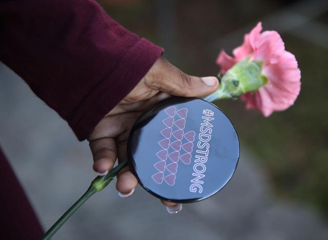 A student holds a flower and a button that reads, #MSDSTRONG, as she arrives for classes at Marjory Stoneman Douglas High School for the first time since the shooting on February 14. (AFP Photo) A student holds a flower and a button that reads, #MSDSTRONG, as she arrives for classes at Marjory Stoneman Douglas High School for the first time since the shooting on February 14. (AFP Photo)