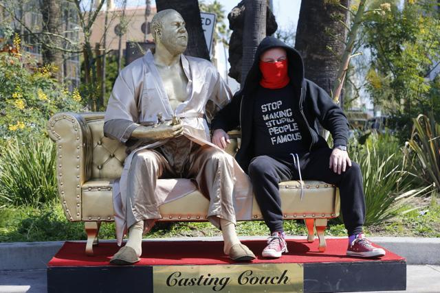 Los Angeles street artist Plastic Jesus sits on his art installation showing a bathrobe-clad Harvey Weinstein. (AP) Los Angeles street artist Plastic Jesus sits on his art installation showing a bathrobe-clad Harvey Weinstein. (AP)
