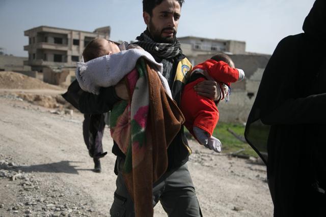 A Syrian civil defence volunteer carries children as he helps them try to flee their homes in the town of Hamouria in Syria's besieged eastern Ghouta region on March 4, following reported air strikes. (AFP Photo) A Syrian civil defence volunteer carries children as he helps them try to flee their homes in the town of Hamouria in Syria's besieged eastern Ghouta region on March 4, following reported air strikes. (AFP Photo)