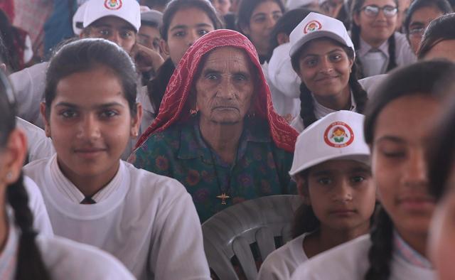 An elderly woman finds a seat with the school girls at a public meeting where Prime Minister Narendra Modi launched national nutrition mission. (Himanshu Vyas/HT Photo)