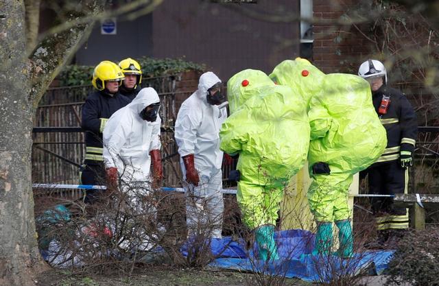 Officials in protective suits check their equipment before repositioning the forensic tent covering the bench where Sergei Skripal and his daughter Yulia were found in the centre of Salisbury, Britain, on March 8, 2018. (Reuters)