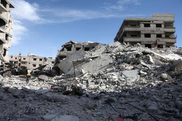 Syrians walk amids the destruction in the rebel-held town of Saqba. (AFP Photo) Syrians walk amids the destruction in the rebel-held town of Saqba. (AFP Photo)