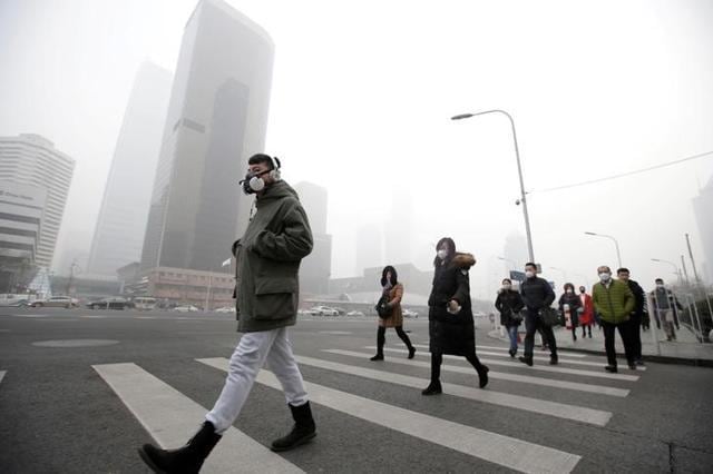 A man wearing a respiratory protection mask walks toward an office building during the smog after a red alert was issued for heavy air pollution in Beijing's central business district on December 21, 2016. (Reuters) A man wearing a respiratory protection mask walks toward an office building during the smog after a red alert was issued for heavy air pollution in Beijing's central business district on December 21, 2016. (Reuters)
