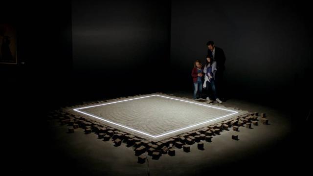 This film began as an art installation and revolves around one too. A square of lighted tiles, on display in a museum courtyard, has a message on social responsibility.