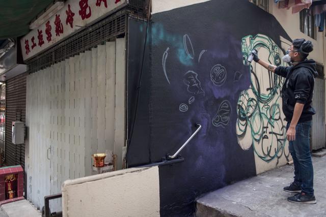 Chinese artist SIK spray paints a mural in an the alley in the Sai Ying Pun district of Hong Kong. (AFP)