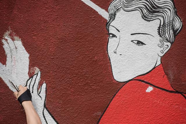 The hand of local artist Neil Wang (bottom L) is seen as he paints a mural onto a wall in Hong Kong. (AFP)