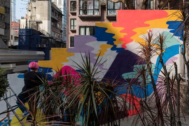 Local artist Zoei Lam paints a mural onto a wall in the Sheung Wan district. (AFP)