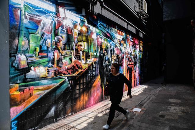 A pedestrian runs past a mural spray painted by British artist Dan Kitchener in an alleyway near a market in the Wanchai district. (AFP)
