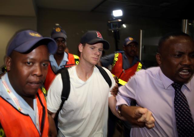 Axed Australian cricket captain Steve Smith is escorted by Police officers as he leaves the O.R. Tambo International Airport in Johannesburg, South Africa March 28, 2018. (REUTERS) Axed Australian cricket captain Steve Smith is escorted by Police officers as he leaves the O.R. Tambo International Airport in Johannesburg, South Africa March 28, 2018. (REUTERS)