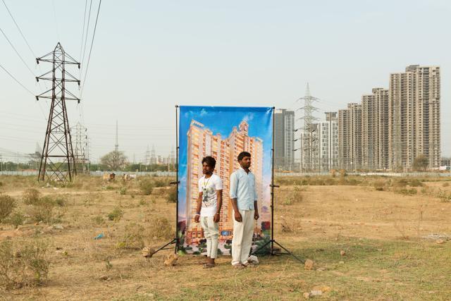 Two locals pose against the backdrop of a real estate ad, as part of Arthur Crestani’s photography project. (Arthur Crestani)