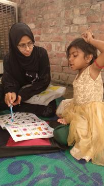 An educator from Aaghaaz-e-Taleem teaches one of the slum kids.