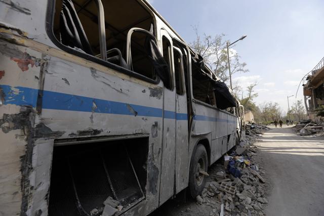 This picture taken on April 14, 2018 shows a destroyed bus near the wreckage of a building described as part of the Scientific Studies and Research Centre (SSRC) compound. (AFP)