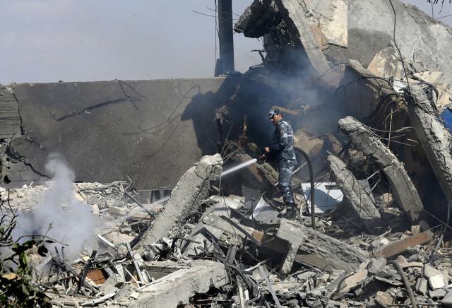 A Syrian soldier spray water on the wreckage of a building. (AFP)