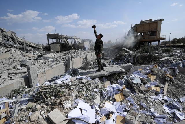 A Syrian soldier films the damage of the Syrian Scientific Research Center which was attacked by US, British and French military strikes, in Barzeh, near Damascus. (AP) A Syrian soldier films the damage of the Syrian Scientific Research Center which was attacked by US, British and French military strikes, in Barzeh, near Damascus. (AP)