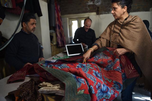 Afghan owner of Zarif Design House Zolaykha Sherzad (R) showing an older traditional chopan (coat) to her employees at the Zarif Design house in Kabul. (AFP) Afghan owner of Zarif Design House Zolaykha Sherzad (R) showing an older traditional chopan (coat) to her employees at the Zarif Design house in Kabul. (AFP)