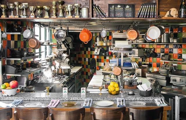 At Machneyuda, there’s an open kitchen and the most coveted seats are right there at the counter, where you can do shots with the chefs. At Machneyuda, there’s an open kitchen and the most coveted seats are right there at the counter, where you can do shots with the chefs.