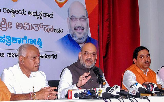 BJP national president Amit Shah, flanked by state president BS Yeduyurappa (L) and BJP MP Prahlad Joshi (R), at a press conference during his state tour ahead of Karnataka Assembly Elections, in Davanagere. (PTI File Photo) BJP national president Amit Shah, flanked by state president BS Yeduyurappa (L) and BJP MP Prahlad Joshi (R), at a press conference during his state tour ahead of Karnataka Assembly Elections, in Davanagere. (PTI File Photo)