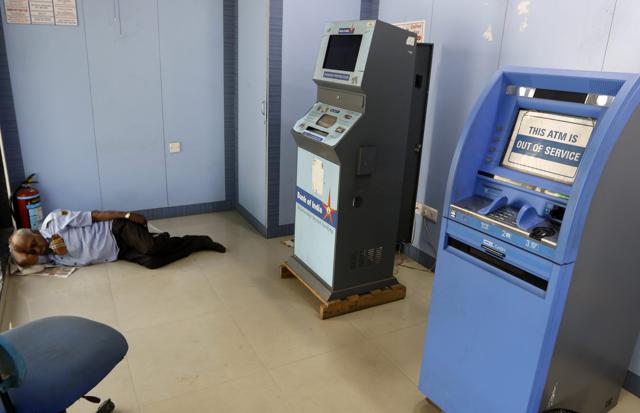 A security guard sleeps near an 'out of service' ATM machine in Ahmedabad on April 17. (PTI Photo) A security guard sleeps near an 'out of service' ATM machine in Ahmedabad on April 17. (PTI Photo)
