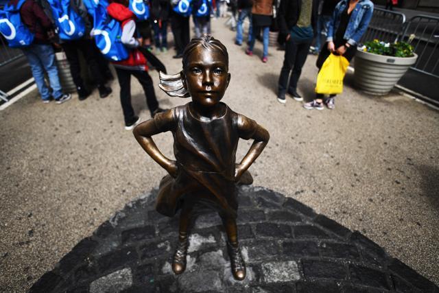 The Fearless Girl statue stands facing the Charging Bull as tourists take pictures in New York. (AFP)
