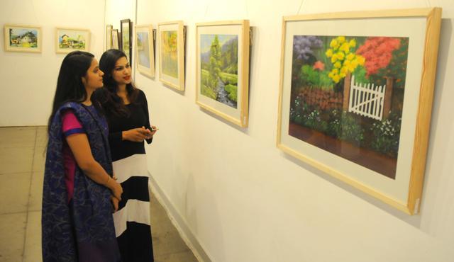 Visitors viewing paintings by Abhimanyu Sekhon in Chandigarh on Saturday. (Anil Dayal/HT)