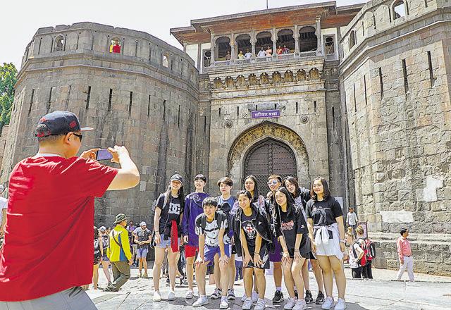 Badminton players from China pose for a photo in front of Shaniwarwada in Pune on April 23. (RAHUL RAUT/HT PHOTO)