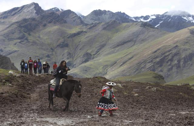 A group of tourists ride horses led by an Andean guide to Rainbow Mountain, a ridge of multicolored sediments laid down millions of years ago and pushed up as tectonic plates clashed. (AP) A group of tourists ride horses led by an Andean guide to Rainbow Mountain, a ridge of multicolored sediments laid down millions of years ago and pushed up as tectonic plates clashed. (AP)