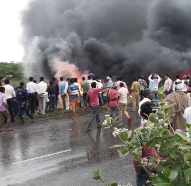 Locals gather around the bus after a fire broke out following an accident on NH 28, Bihar. (ANI/Twitter)