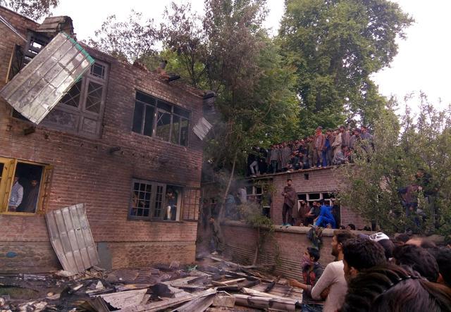 People look on the damaged house where top militant commanders, including Sadaam Padar and assistant professor of Kashmir University turned militant Mohamaad Raafi, and three other militants were hiding before they were killed during an encounter, at Badigam in Shopian district of south Kashmir on Sunday. (PTI) People look on the damaged house where top militant commanders, including Sadaam Padar and assistant professor of Kashmir University turned militant Mohamaad Raafi, and three other militants were hiding before they were killed during an encounter, at Badigam in Shopian district of south Kashmir on Sunday. (PTI)