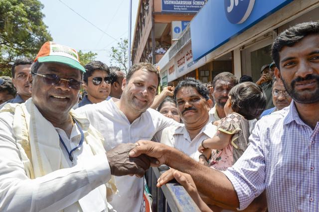 Congress President Rahul Gandhi (C) and Karnataka Chief Minister Siddaramaiah (L) shake hands with their party supporters during a campaign ahead of Karnataka elections in Honnavar (PTI) Congress President Rahul Gandhi (C) and Karnataka Chief Minister Siddaramaiah (L) shake hands with their party supporters during a campaign ahead of Karnataka elections in Honnavar (PTI)