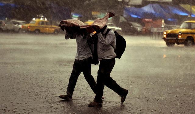 Two men use a plastic sheet to protect themselves as it rains in Kolkata. (PTI Photo) Two men use a plastic sheet to protect themselves as it rains in Kolkata. (PTI Photo)