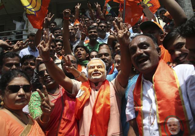 A supporter of Bharatiya Janata Party (BJP) wearing a mask of Prime Minister Narendra Modi flashes victory sign as he celebrates early leads for the party in the Karnataka state elections in Bengaluru. (AP File Photo) A supporter of Bharatiya Janata Party (BJP) wearing a mask of Prime Minister Narendra Modi flashes victory sign as he celebrates early leads for the party in the Karnataka state elections in Bengaluru. (AP File Photo)