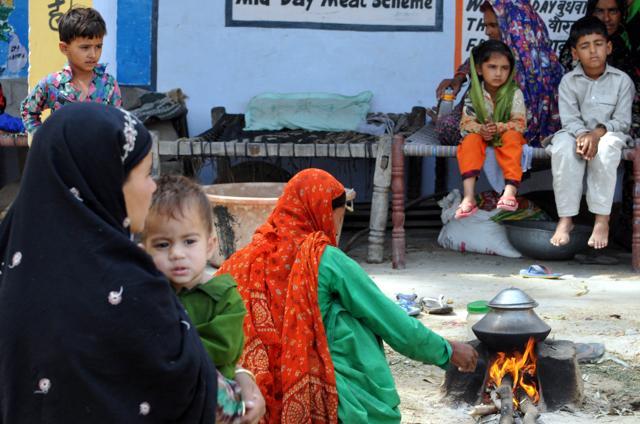 A woman prepares food at a shelter camp in Jora village she has shifted to along with her family after firing by Pakistan Rangers along the international border on Tuesday. (Nitin Kanotra /HT photo)