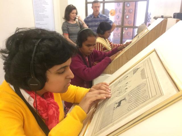 Young girls feel and read the descriptions of artworks that are put up in Braille.