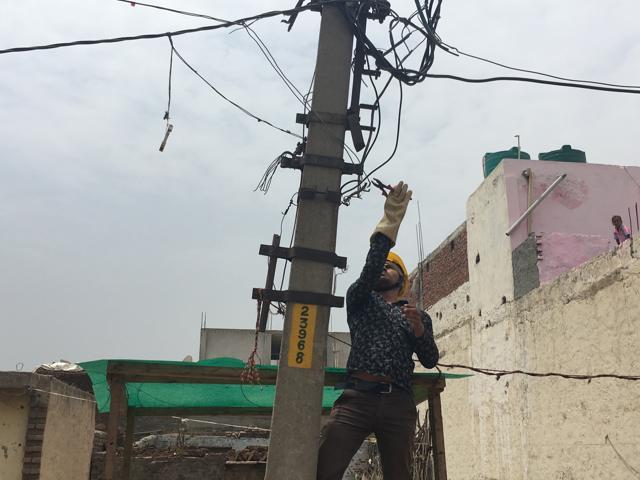 A line man from the Noida Power Corporation Limited removes unauthorised cables in Greater Noida’s Surajpur village, a task that officials say puts them on the receiving end of people’s anger. (Singdha Poonam/HT Photo) A line man from the Noida Power Corporation Limited removes unauthorised cables in Greater Noida’s Surajpur village, a task that officials say puts them on the receiving end of people’s anger. (Singdha Poonam/HT Photo)