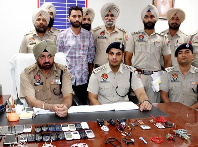 Jail officials showing mobile phones seized from inmates during a raid at the central jail in Amritsar last year. (HT File ) Jail officials showing mobile phones seized from inmates during a raid at the central jail in Amritsar last year. (HT File )