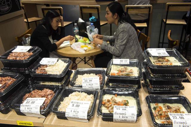 Office workers eat their lunch sitting next to food items packaged in plastic containers in Bangkok. (AFP Photo)
