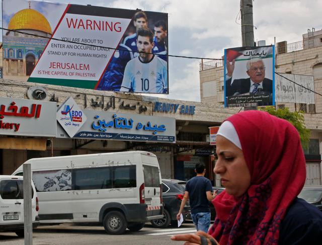 A picture taken on June 5, 2018, shows a poster erected on a main street in the West Bank town of Hebron next to a portrait of the Palestinian president Mahmud Abbas (R), denouncing the upcoming friendly football match between Argentina and Israel and calling Argentina's star Lionel Messi (portrait) to boycott the match. (AFP) A picture taken on June 5, 2018, shows a poster erected on a main street in the West Bank town of Hebron next to a portrait of the Palestinian president Mahmud Abbas (R), denouncing the upcoming friendly football match between Argentina and Israel and calling Argentina's star Lionel Messi (portrait) to boycott the match. (AFP)