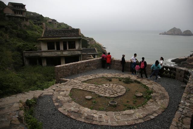 Tourists next to an abandoned building in Houtouwan. (AP) Tourists next to an abandoned building in Houtouwan. (AP)