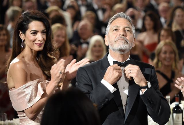 George Clooney, right, adjusts his bow tie as he arrives in the ballroom at the 46th AFI Life Achievement Award honoring him at the Dolby Theatre, Thursday, June 7, 2018, in Los Angeles. Looking on at left is his wife and human rights lawyer Amal. (AP) George Clooney, right, adjusts his bow tie as he arrives in the ballroom at the 46th AFI Life Achievement Award honoring him at the Dolby Theatre, Thursday, June 7, 2018, in Los Angeles. Looking on at left is his wife and human rights lawyer Amal. (AP)