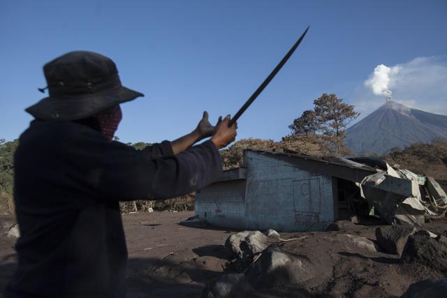 Gilberto Rosales, from the nearby village El Rodeo, motions towards the Volcan de Fuego, or Volcano of Fire, as he retells how he saw the lava flow during it deadly eruption, while he passes through the devastated hamlet of San Miguel Los Lotes, Guatemala. (AP) Gilberto Rosales, from the nearby village El Rodeo, motions towards the Volcan de Fuego, or Volcano of Fire, as he retells how he saw the lava flow during it deadly eruption, while he passes through the devastated hamlet of San Miguel Los Lotes, Guatemala. (AP)
