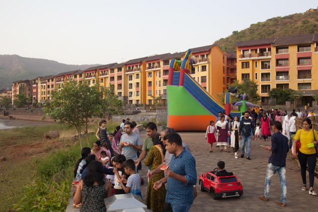 Pedestrians walk past an inflatable slide as residential buildings stand in the background in Lavasa on May 12, 2018. (Bloomberg) Pedestrians walk past an inflatable slide as residential buildings stand in the background in Lavasa on May 12, 2018. (Bloomberg)