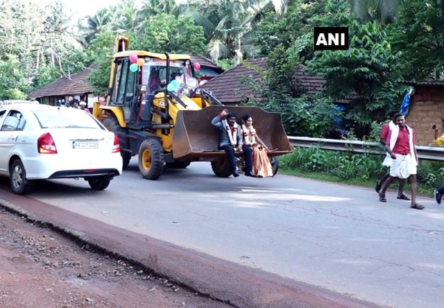 Couple riding on a JCB after their wedding (ANI)