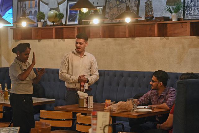 A server communicates in sign language at Mirchi &amp; Mime in Mumbai, which employs speech and hearing impaired persons. The key is to maintain high standards, says co-founder Prashant Issar. ‘People may come for the experience, but they come back for the food, and the great service.’ (Satyabrata Tripathy/HT Photo)