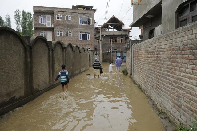 People walk down a flooded street after heavy rains in kursoo rajbagh area of Srinagar, India, 30 June 2018. (Waseem Andrabi / HT Photo) People walk down a flooded street after heavy rains in kursoo rajbagh area of Srinagar, India, 30 June 2018. (Waseem Andrabi / HT Photo)